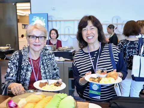 Two women smiling and holding breakfast plates at the AdventHealth Women's Health and Cancer Prevention Event