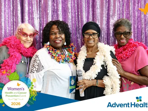 Four women wearing colorful boas pose together at the 2026 AdventHealth Women's Health and Cancer Prevention Event.