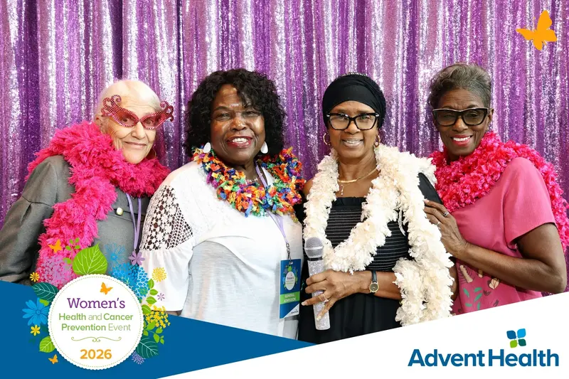 Four women wearing colorful boas pose together at the 2026 AdventHealth Women's Health and Cancer Prevention Event.