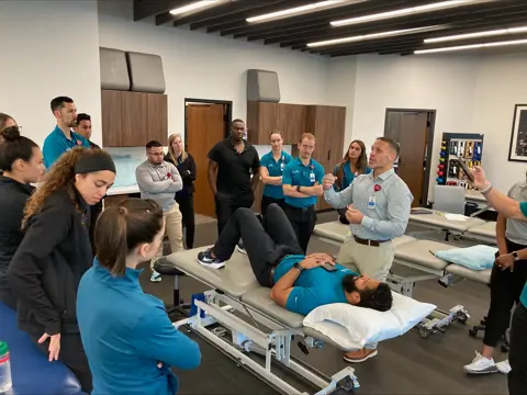Instructor demonstrates with a patient on a therapy table as a group observes.