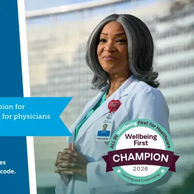 Healthcare professional in scrubs wearing a stethoscope and displaying a Wellbeing First Champion badge for 2026