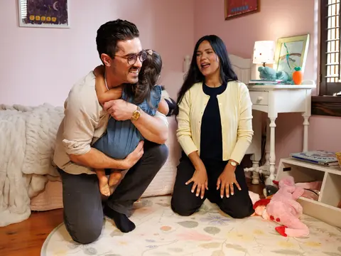 Eddie hugs his daughter while with his wife in his daughter's bedroom.