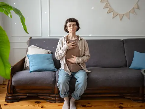 A woman doing breathing exercises on her couch.