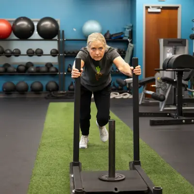 A woman performs a lunge exercise on a workout machine in a gym.