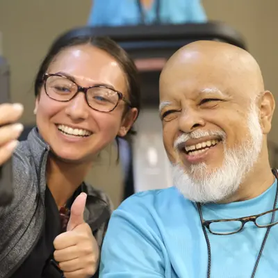 A smiling woman takes a selfie with a smiling man in a gym.