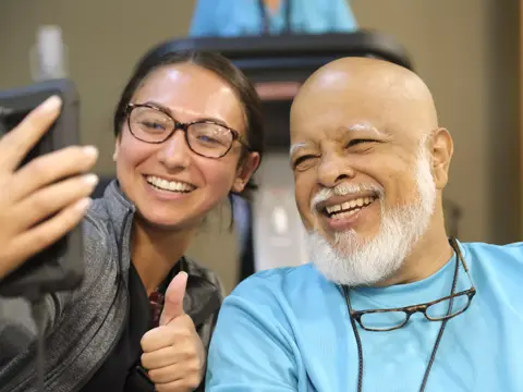 A smiling woman takes a selfie with a smiling man in a gym.