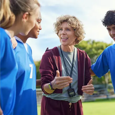 Coach speaking to a student athlete team wearing blue uniforms