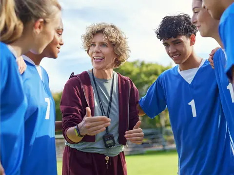 Coach speaking to a student athlete team wearing blue uniforms