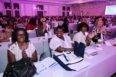 Attendees smiling and applauding during a women's health event in a conference ballroom