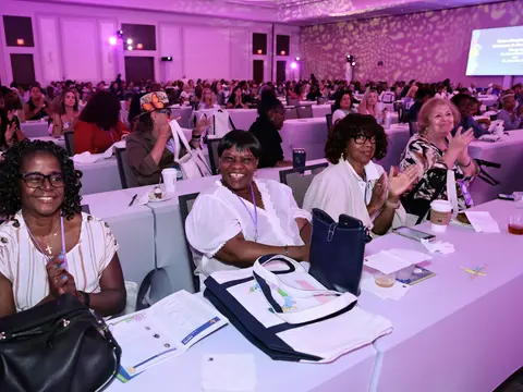 Attendees smiling and applauding during a women's health event in a conference ballroom