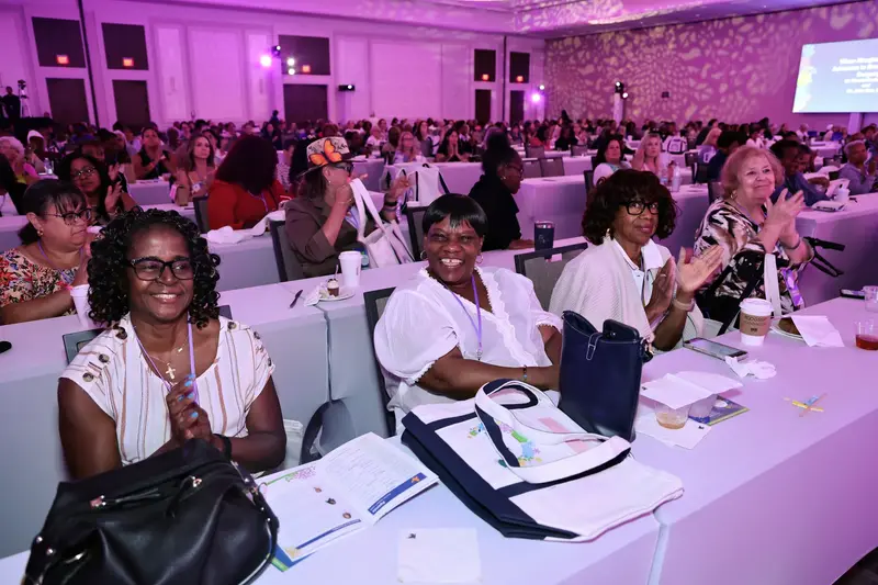 Attendees smiling and applauding during a women's health event in a conference ballroom