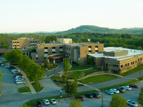 Aerial view of AdventHealth hospital with parking lots filled with cars and lush greenery.