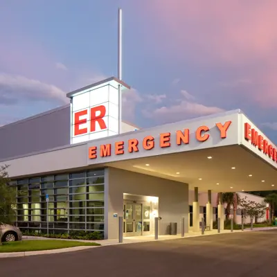Exterior view of AdventHealth Westchase Emergency Room entrance at dusk with illuminated ER signage and covered drive-through area