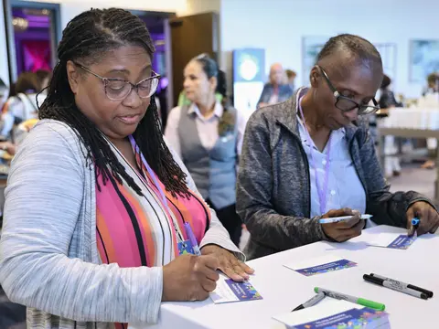 Two women writing messages on cards during the AdventHealth Women’s Health and Cancer Prevention Event.