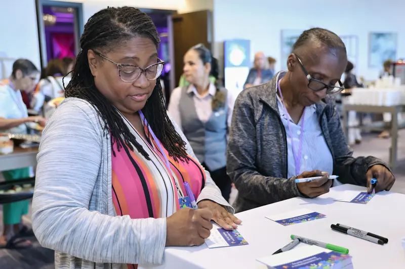Two women writing messages on cards during the AdventHealth Women’s Health and Cancer Prevention Event.