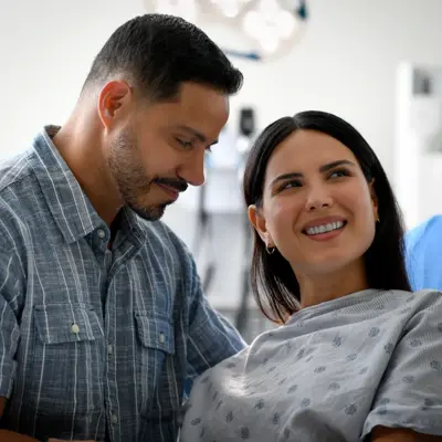 A smiling man and woman in a hospital room, showing support and care.