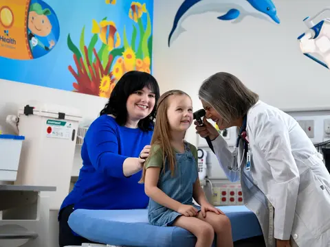 Doctor examining a young girl with a stethoscope in a pediatric clinic.