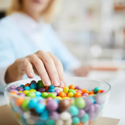 A hand reaching for a bowl of candy.