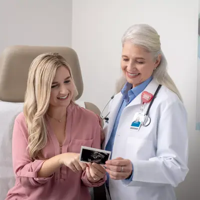 A smiling doctor shows a patient an ultrasound image in a medical office.