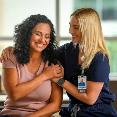 A smiling nurse administers a vaccine to a happy patient, both wearing ID badges.
