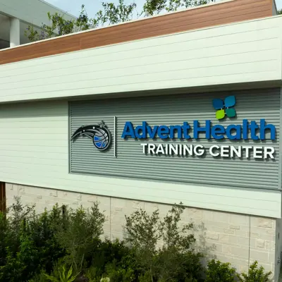 AdventHealth Training Center sign on a building with greenery and a clear sky.