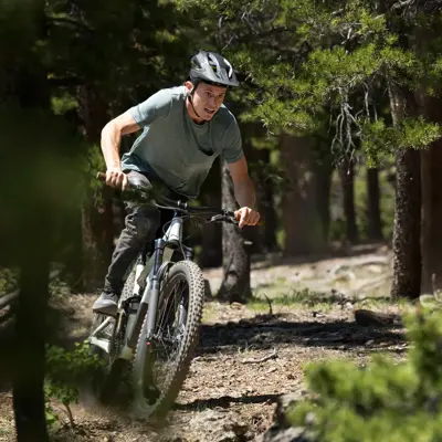 A man riding a mountain bike on a dirt trail in a forest.