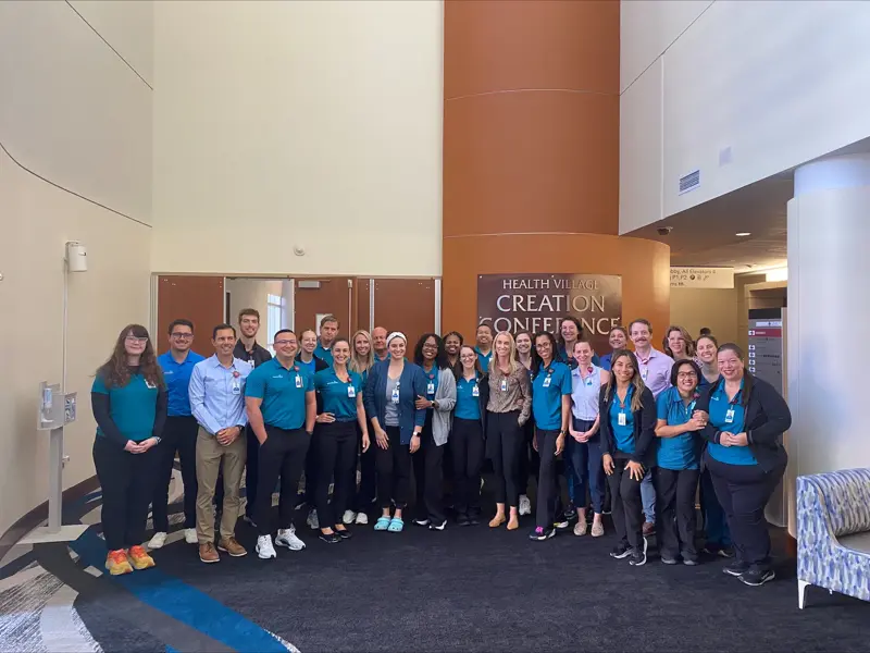 Large group poses together in front of a conference center sign.