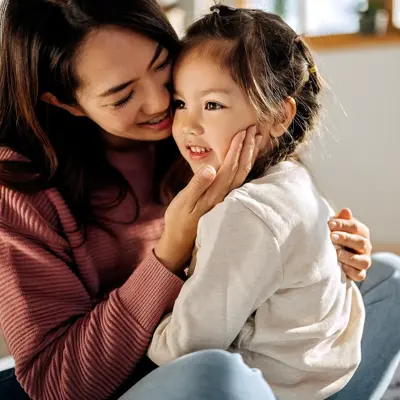 A young woman holding her little girl and smiling.