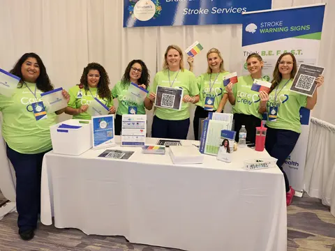AdventHealth team members at a Stroke Services booth displaying stroke warning signs and educational materials at a women’s health event.