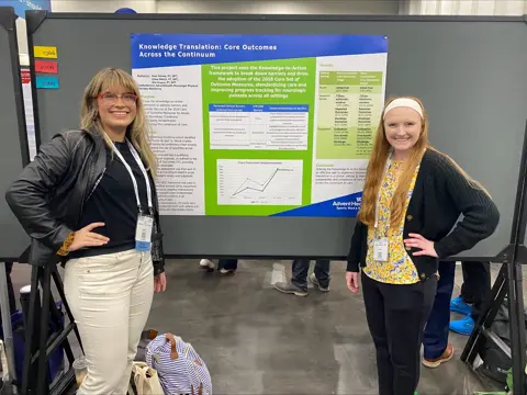 Two people pose with a poster on knowledge translation in physical therapy.