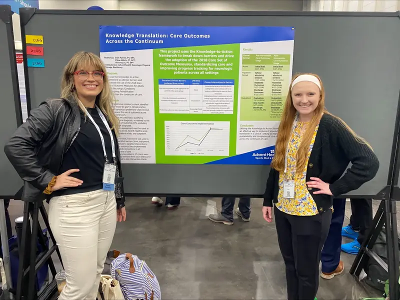 Two people pose with a poster on knowledge translation in physical therapy.