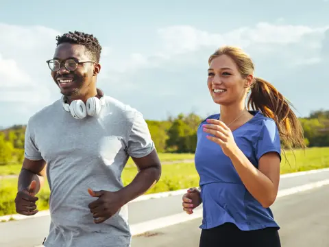 A young man and woman running outdoors.