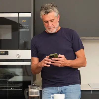 A middle-aged man using his phone in the kitchen.
