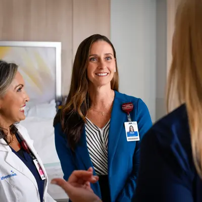 Three AdventHealth employees in a hospital room, smiling and conversing.