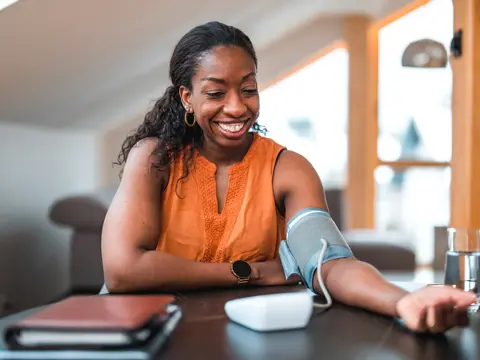 A woman checking her blood pressure at home.