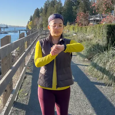 A woman check her watch while walking on a trail.