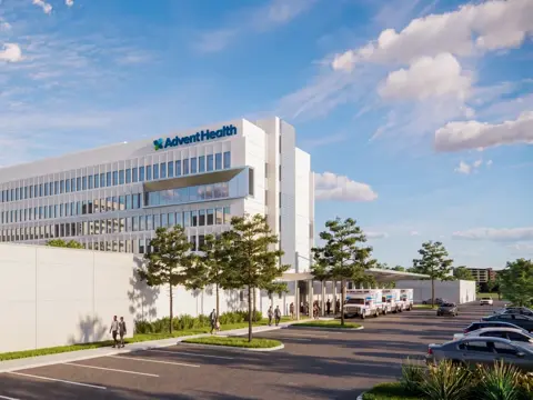 Exterior rendering of the modern AdventHealth Carrollwood Garden Tower expansion building with glass facade, featuring landscaped grounds, parking area, and people walking near the entrance under a blue sky with clouds
