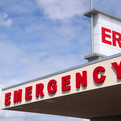 Emergency room sign with ER above and EMERGENCY below, against a blue sky background.