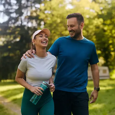 Young couple in athletic wear walking together and smiling in a sunny park
