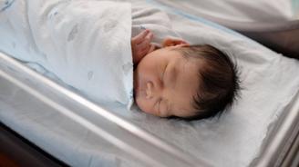 Newborn baby in their hospital cot, fast asleep.