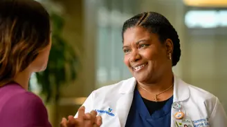 Nurse Tammy B. smiling and engaging in conversation with a patient in a hospital setting.