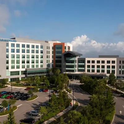 Aerial view of AdventHealth hospital with many cars parked in front.