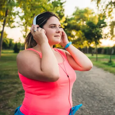 A woman wearing taking a break from a run along a trail.