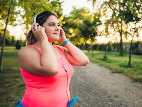 A woman wearing taking a break from a run along a trail.