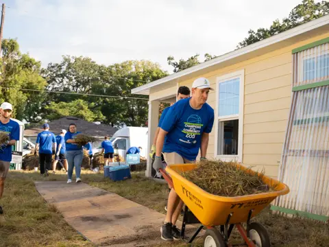 A man pushing a wheelbarrow at a charity event.