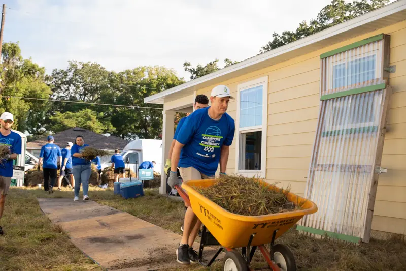 A man pushing a wheelbarrow at a charity event.