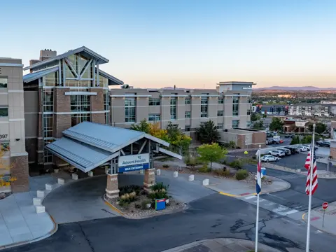 Aerial view of AdventHealth Alpine hospital entrance with flags and parked cars.