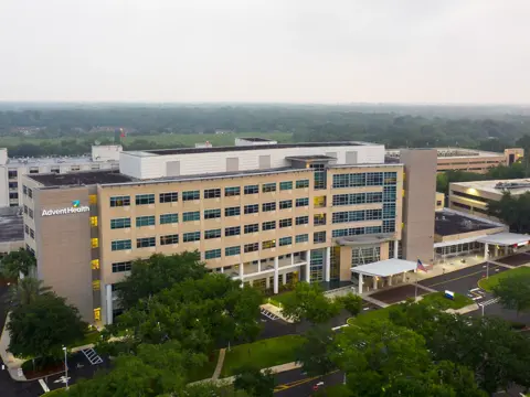 Aerial view of AdventHealth hospital with multiple buildings, trees, and a parking lot.
