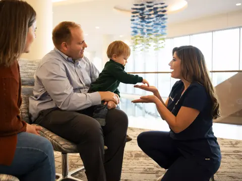 A family consults with a nurse in a hospital setting, focusing on a young child.