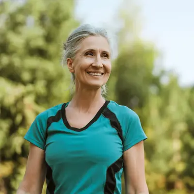 smiling senior woman exercising outdoors in a park.